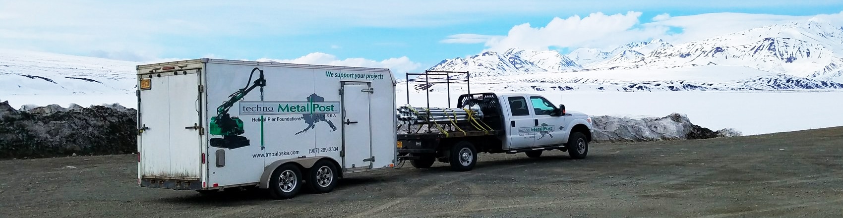 Techno Metal Post truck hauling trailer with equipment through snowy Alaskan mountains.